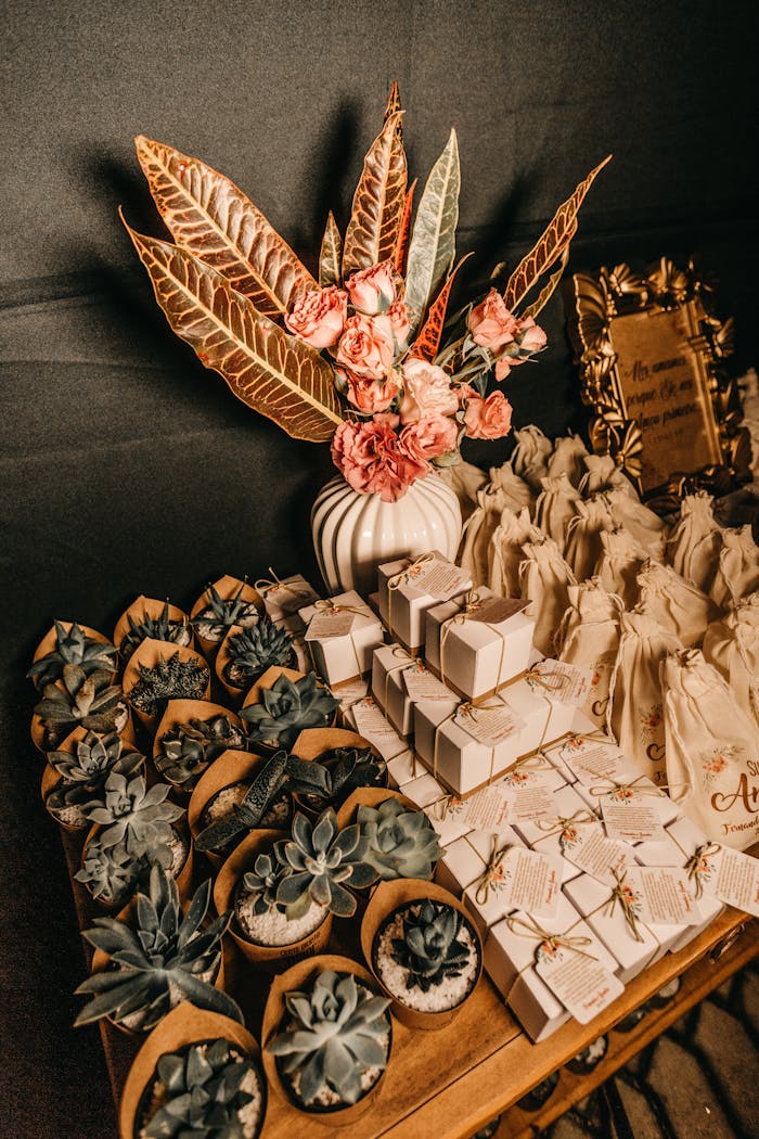 Elegant arrangement of succulents and flowers with gift boxes on a decorated table.